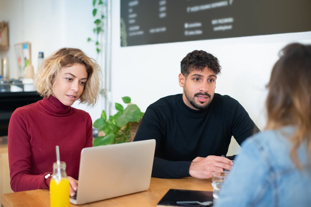 Diverse group collaborating in a modern office setting with laptops and drinks.