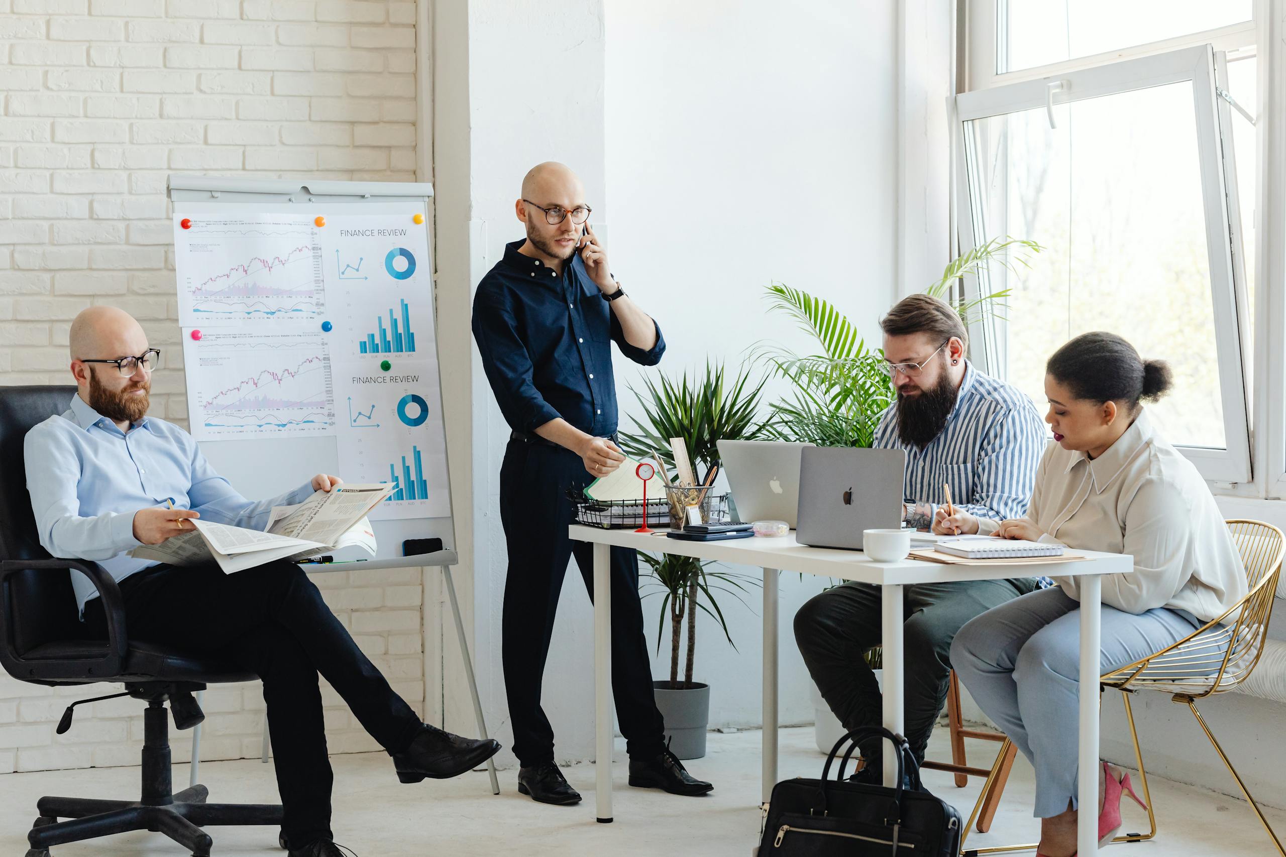 A diverse group of coworkers collaborating in a contemporary office setting with laptops and charts.