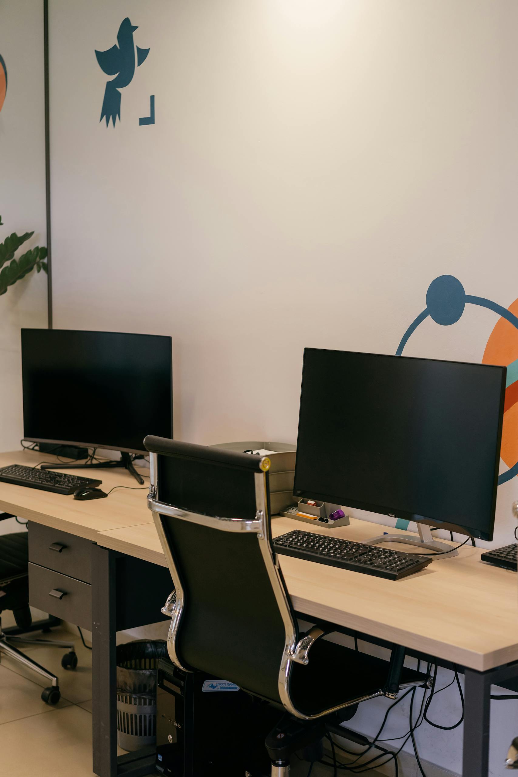 Empty modern office space with two desks, monitors, and stylish chairs.